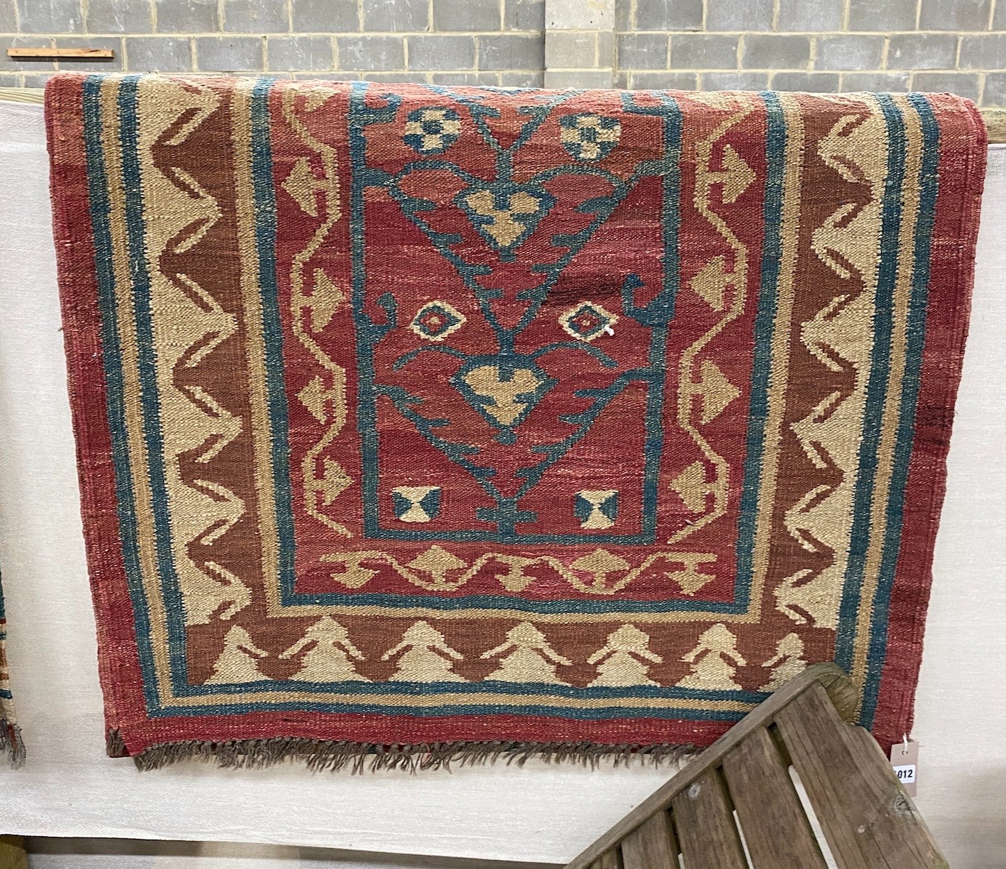 A Kilim runner with geometric motifs on a red ground, 394 x 96cm